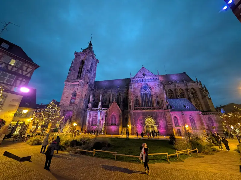 The Collégiale Saint-Martin lit purple above the market — the Christmas market in Colmar, France