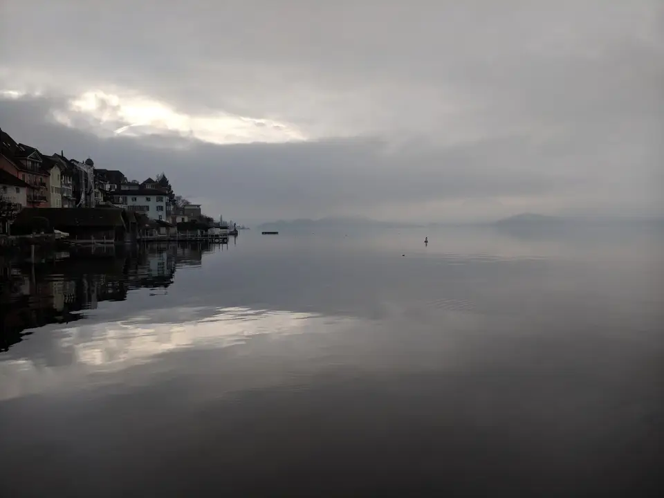 The lake flat calm under a gray sky